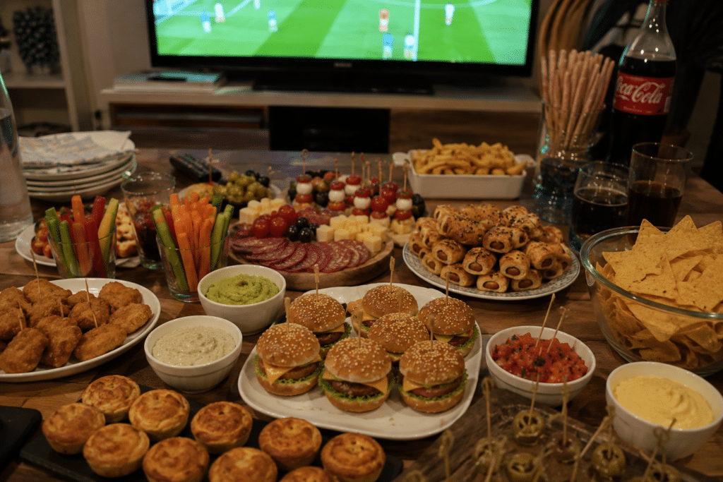 Buffet apéritif pour regarder un match de football avec mini burgers, nachos, feuilletés, crudités et planche apéro devant la télévision.